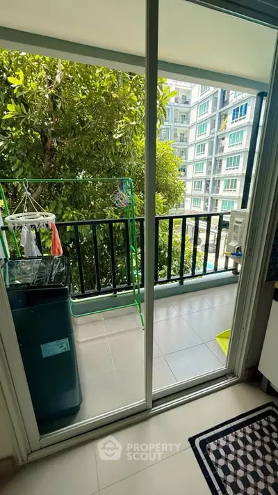 Charming balcony view with lush greenery and modern apartment buildings.