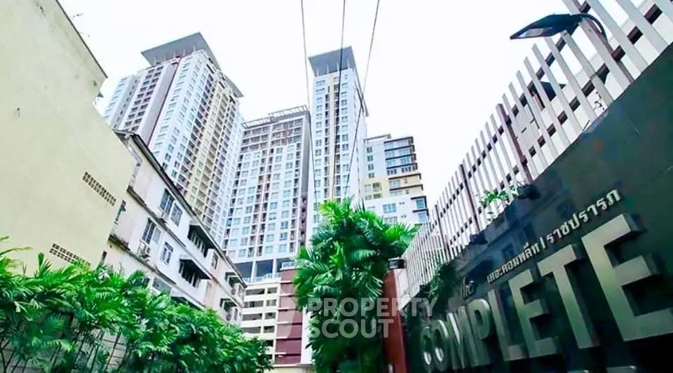 Modern high-rise condominium with lush greenery and secure entrance in urban setting.