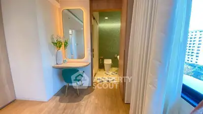 Modern bedroom with elegant vanity and ensuite bathroom, featuring stylish decor and natural light.
