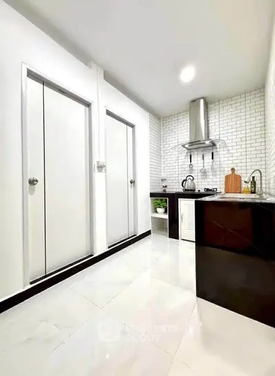 Modern kitchen with sleek design, featuring white brick backsplash and stainless steel appliances.