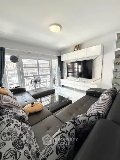 Spacious modern living room with large TV and stylish decor, perfect for relaxation and entertainment.