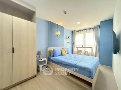 Modern bedroom with blue accents and natural light, featuring a cozy bed and stylish decor.