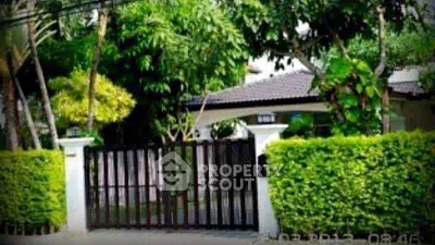 Charming suburban house with lush greenery and gated entrance, perfect for privacy and tranquility.