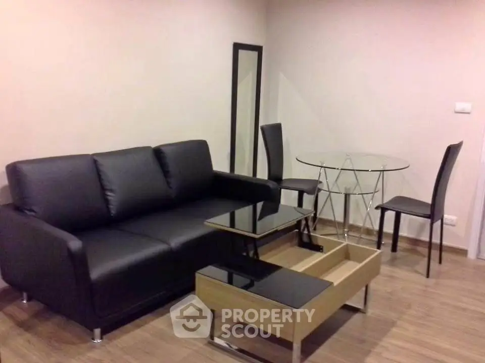 Modern living room with sleek black sofa and glass dining table in stylish apartment.
