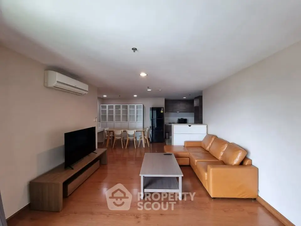 Spacious modern living room with leather sofa and open kitchen layout