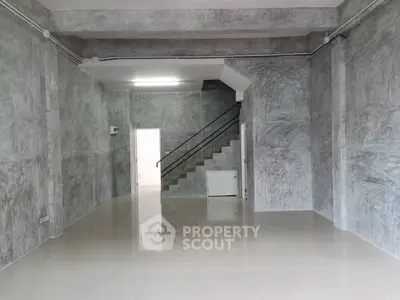 Spacious industrial-style interior with polished concrete walls and sleek staircase