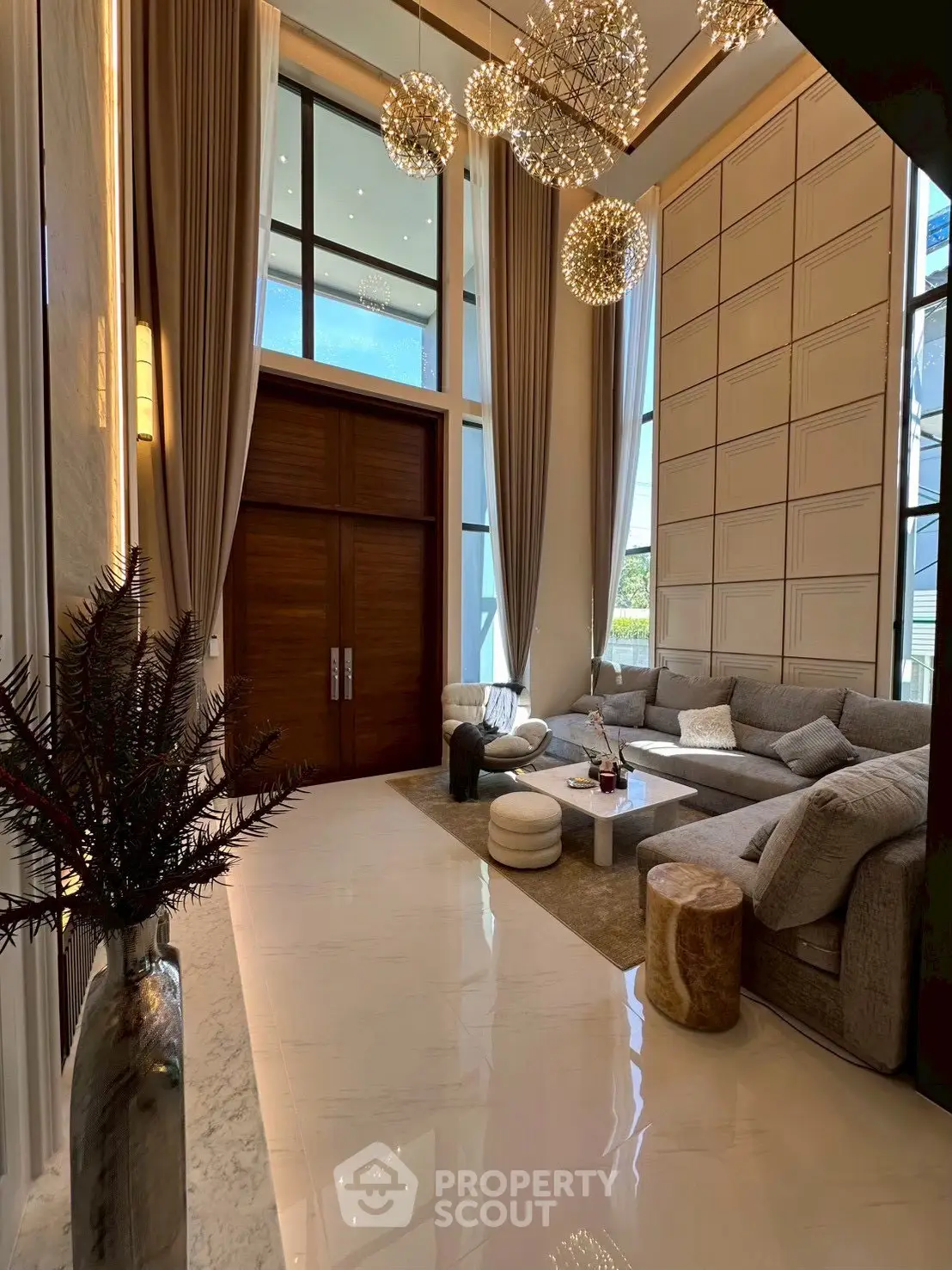 Luxurious living room with high ceilings, elegant chandeliers, and plush seating in a modern home.