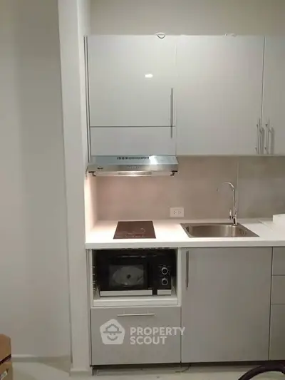 Modern compact kitchen with sleek white cabinets and built-in appliances