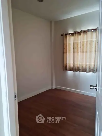 Cozy empty room with wooden flooring and window curtains, perfect for customization.
