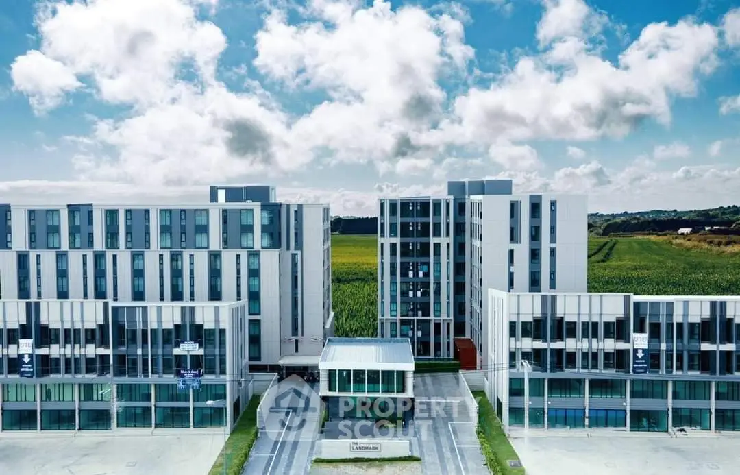 Modern residential complex with sleek architecture and lush surroundings under a vibrant sky.