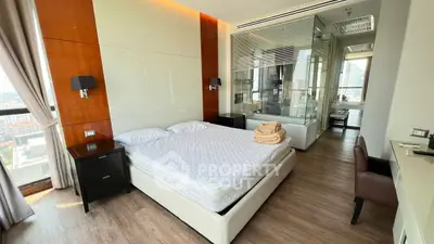 Luxurious bedroom with city view and modern glass-walled bathroom