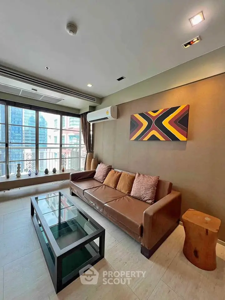 Stylish living room with modern decor and city view, featuring a leather sofa and glass coffee table.