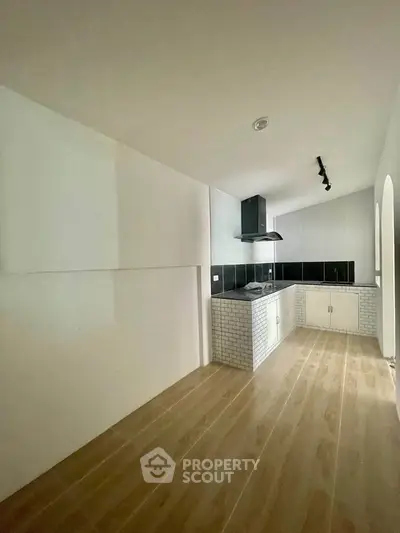 Modern kitchen with sleek black and white design, featuring open layout and stylish wooden flooring.