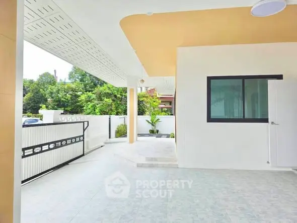 Spacious modern home entrance with covered patio and lush greenery.