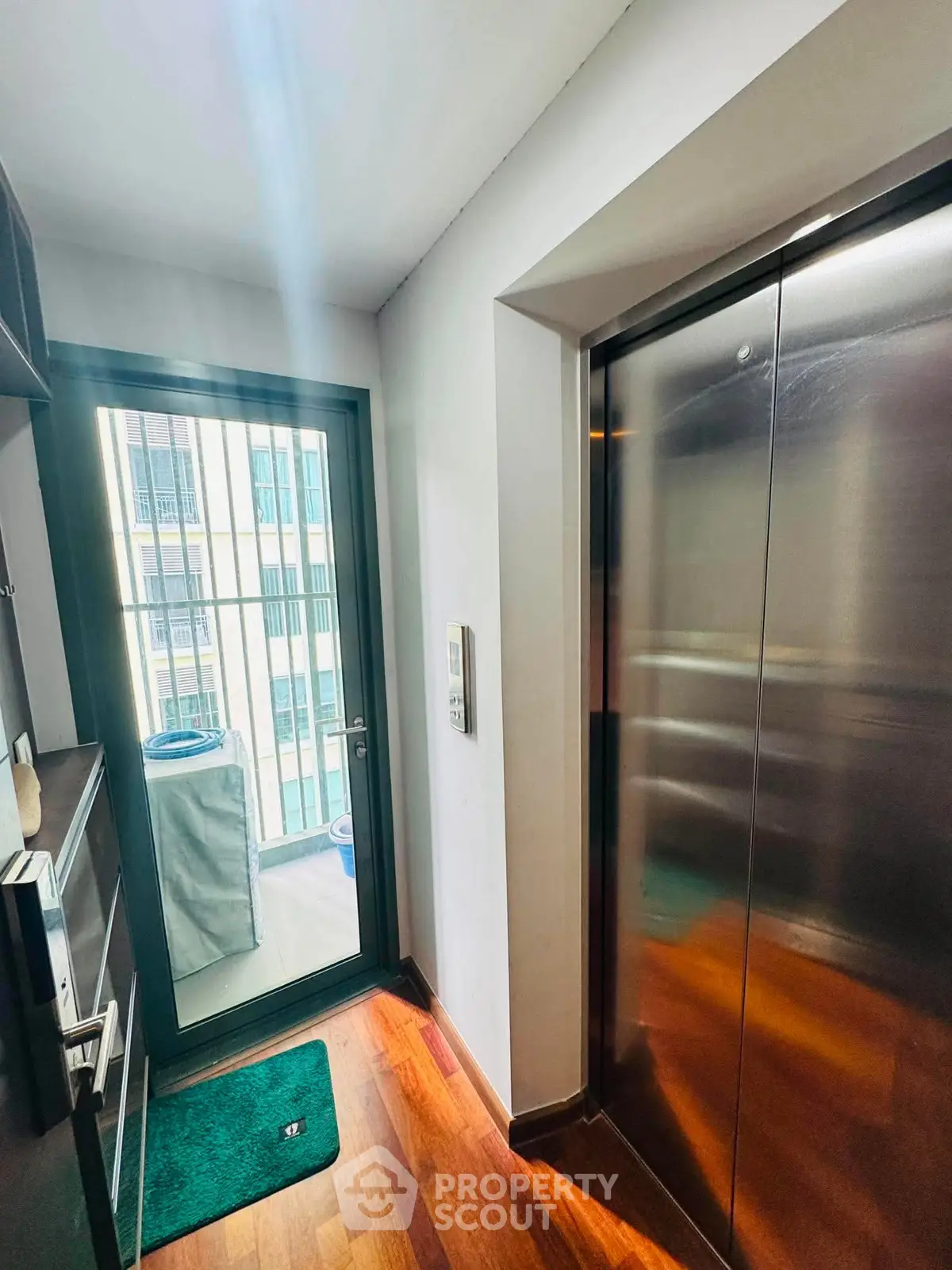 Modern elevator area with sleek design and wooden flooring in a residential building.