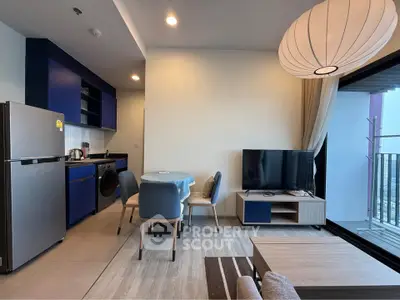 Modern living room with stylish blue kitchen, cozy dining area, and balcony view.
