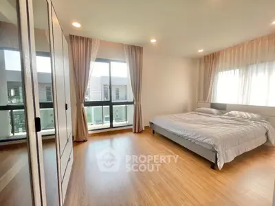 Spacious bedroom with large windows and wooden flooring in modern apartment