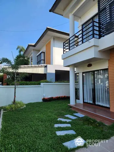 Modern two-story house with lush green lawn and stylish balcony design.