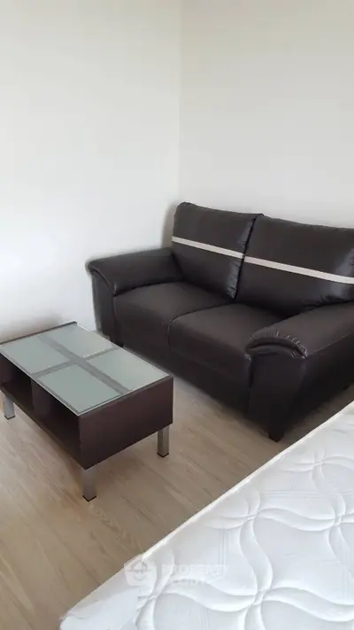 Cozy bedroom with modern sofa and glass-top coffee table, perfect for relaxation.