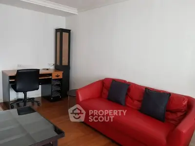 Cozy living room with red sofa and study desk, perfect for relaxation and work.