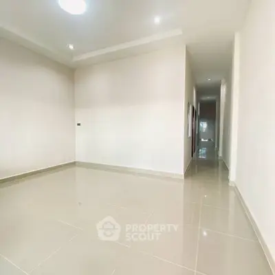 Spacious empty room with glossy tiled flooring and recessed lighting