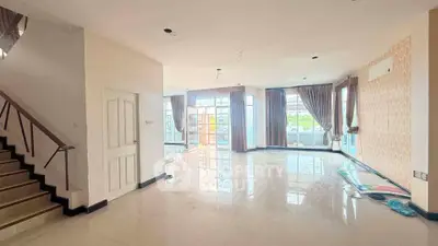 Spacious living room with large windows and elegant curtains, perfect for natural light and modern living.
