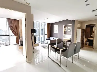 Modern open-plan living room with city view, sleek furniture, and elegant decor in high-rise apartment.