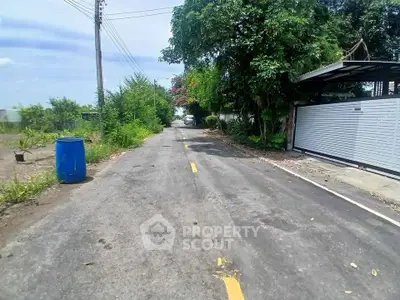 Quiet residential street with lush greenery and gated entrance, perfect for serene living.
