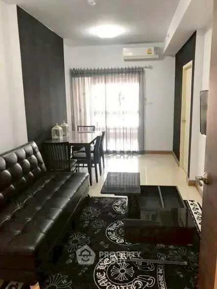 Stylish living room with black leather sofa and modern decor in a cozy apartment.