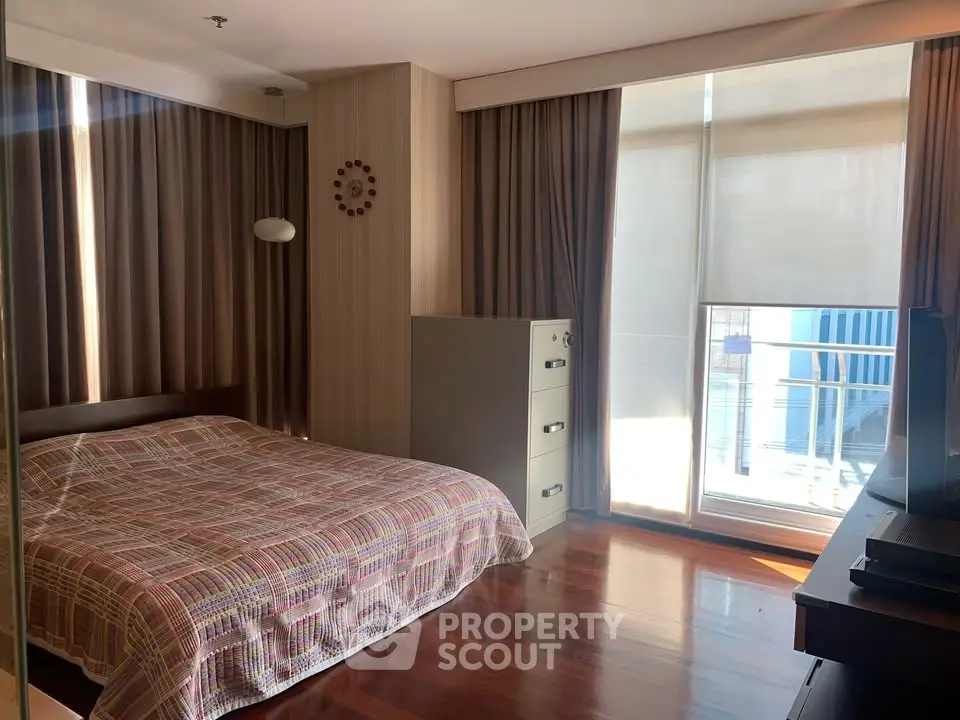 Spacious bedroom with modern decor and large window offering natural light.