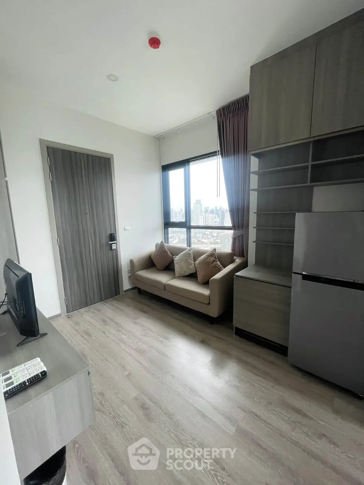 Modern living room with city view, featuring sleek furniture and large window for natural light.