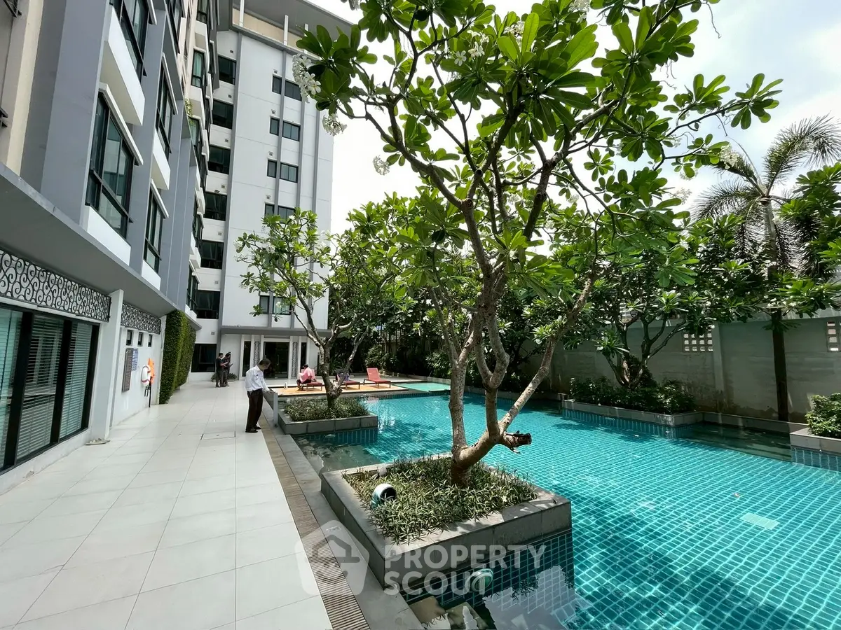 Luxurious apartment complex with serene swimming pool and lush greenery.