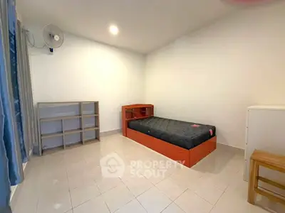 Minimalist bedroom with single bed, shelves, and fan in a bright, tiled room.