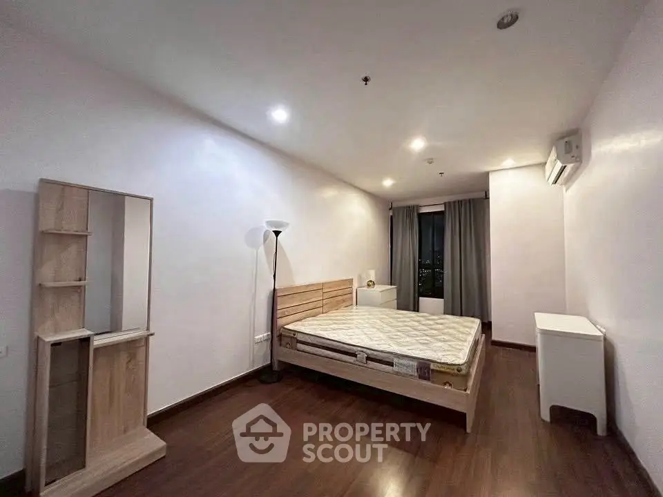 Spacious bedroom with wooden flooring and modern furnishings