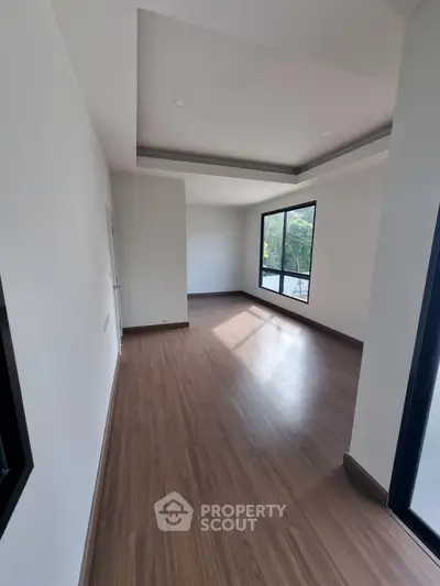 Spacious empty room with large windows and wooden flooring, perfect for customization.