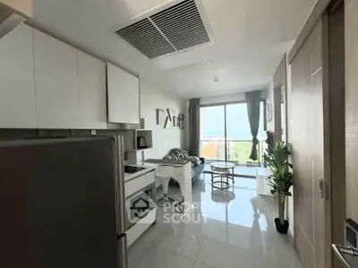 Modern living room with open kitchen and balcony view, featuring sleek design and natural light.