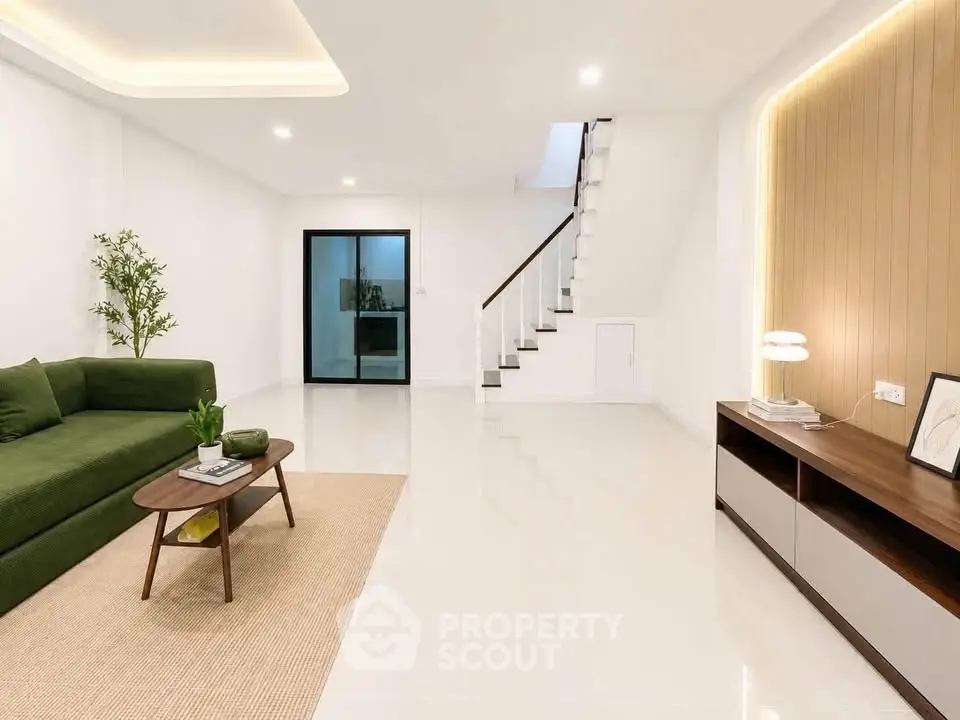 Spacious modern living room with green sofa and elegant staircase