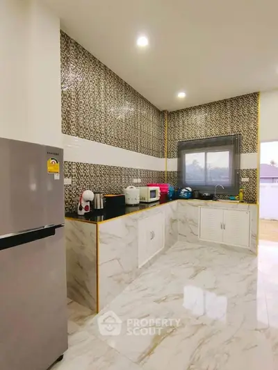 Modern kitchen with marble flooring and sleek appliances in a stylish home.