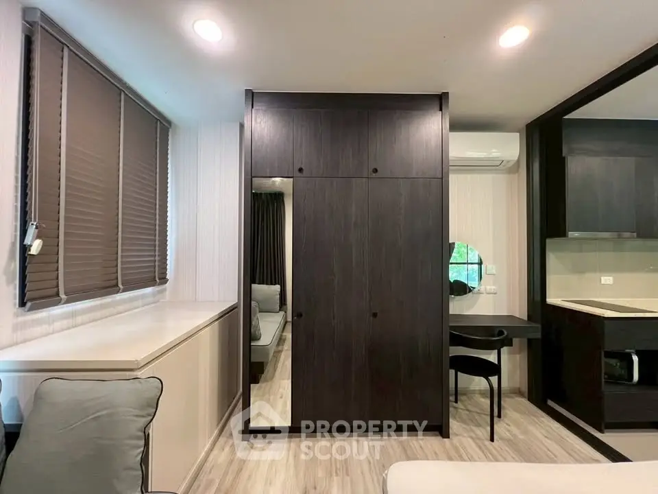 Modern apartment interior with sleek dark wood furniture and open layout, featuring a cozy living area and stylish kitchen.