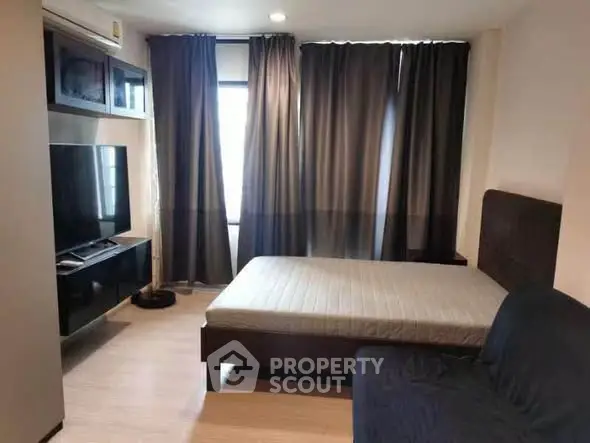 Modern bedroom with large TV and stylish curtains in a cozy apartment.