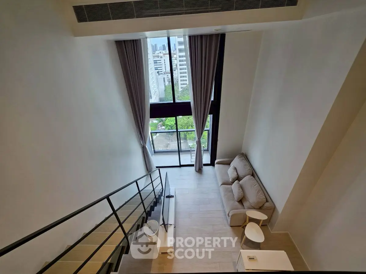 Stunning loft apartment with high ceilings and large windows offering a beautiful city view.