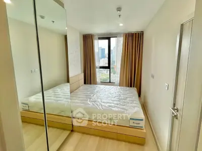 Modern bedroom with city view, mirrored closet, and natural light in a high-rise apartment.