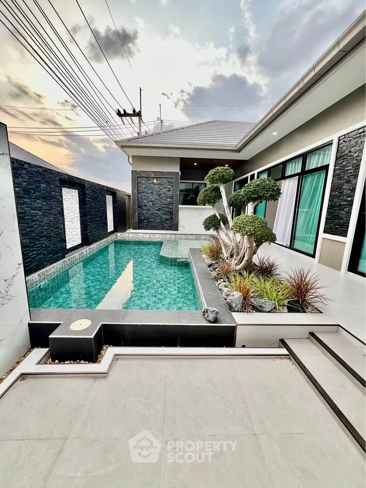 Luxurious modern home with private pool and stylish landscaping at sunset.