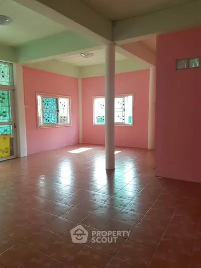 Spacious pink-walled room with tiled flooring and natural light, ideal for versatile use.