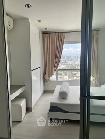 Modern bedroom with city view, featuring sleek white furniture and large window for natural light.