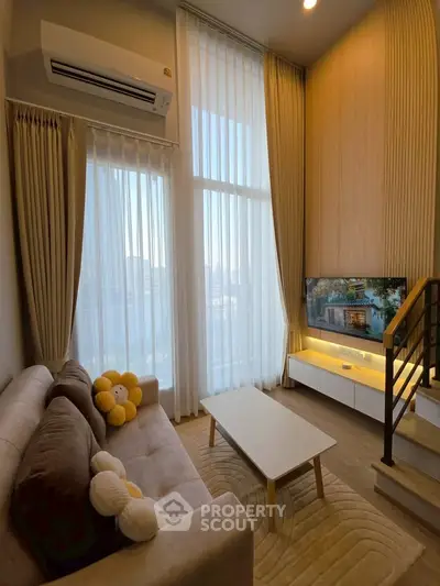 Stylish modern living room with high ceilings and large windows, featuring cozy sofa and wall-mounted TV.