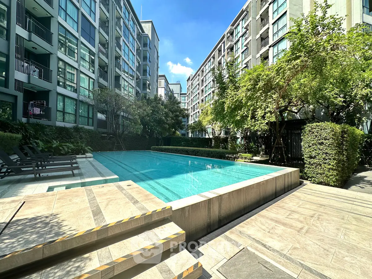 Luxurious condominium pool area with modern design and lush greenery, perfect for relaxation and leisure.