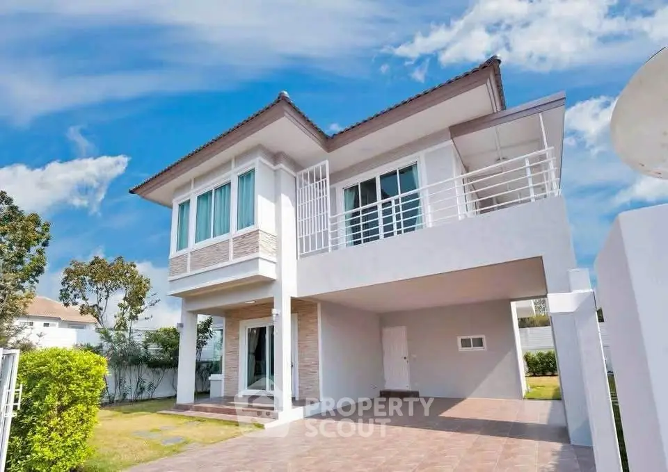 Modern two-story house with spacious driveway and lush greenery under a clear blue sky.