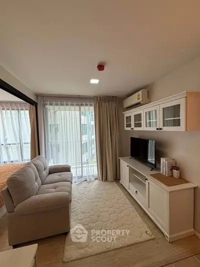 Cozy living room with plush sofa, TV unit, and large windows for natural light.