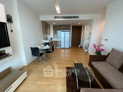 Modern living room with open kitchen, stylish furniture, and wooden flooring in a contemporary apartment.